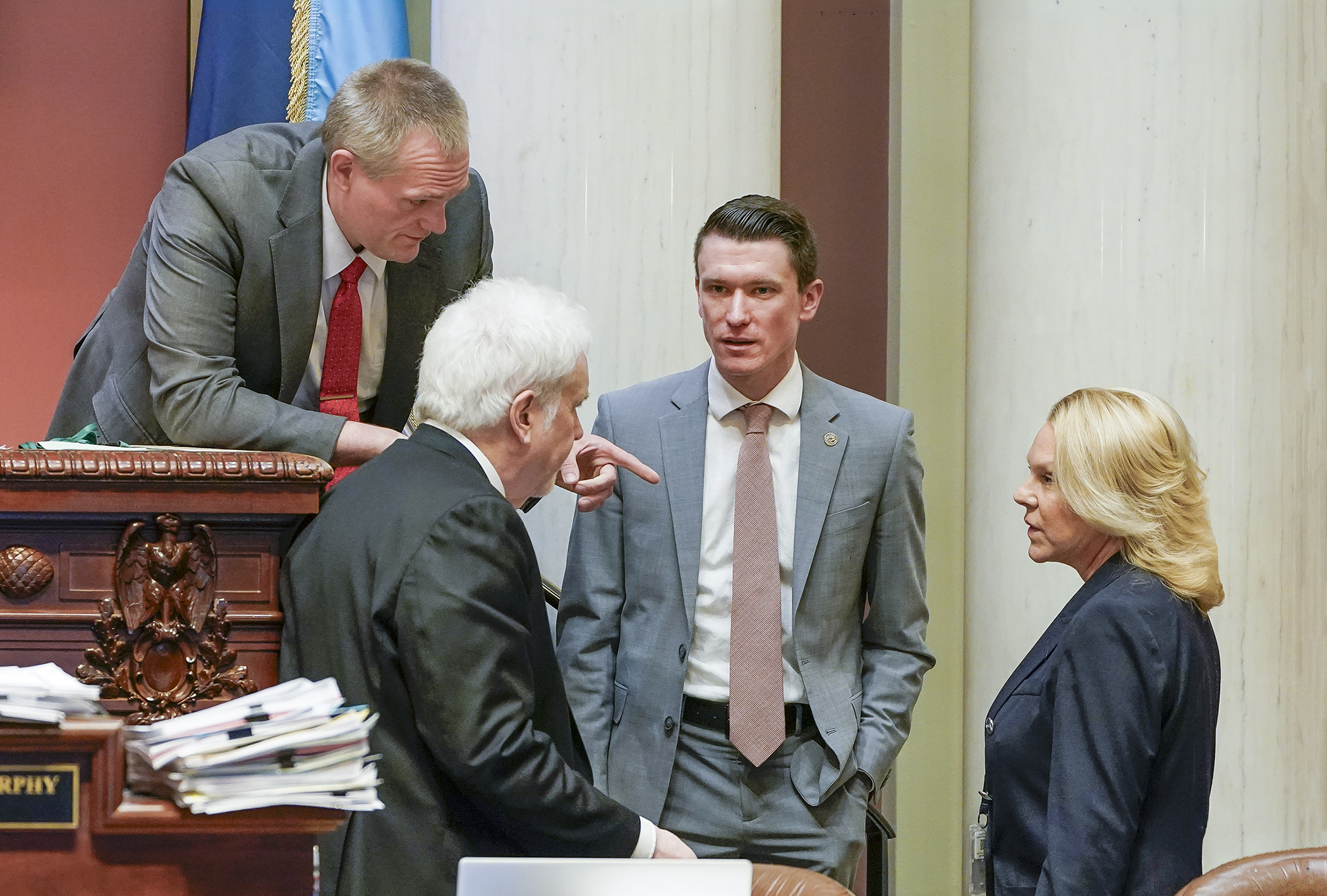 Rep. Matt Norris, center, who sponsors HF1338/SF856*, and Rep. Patti Anderson consult with Speaker Pro Tempore Bjorn Olson, left, and Chief Clerk Patrick Murphy during a May 7 floor recess. (Photo by Andrew VonBank)